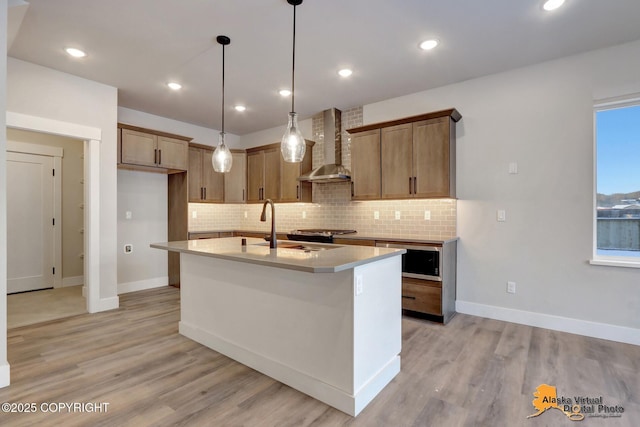 8803 Chalk Hill Loop, Anchorage, AK 99502 - kitchen with wall chimney range hood, stainless steel microwave, backsplash, a kitchen island with sink, and recessed lighting