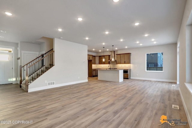 8803 Chalk Hill Loop, Anchorage, AK 99502 - unfurnished living room featuring stairway, light wood-style flooring, and recessed lighting