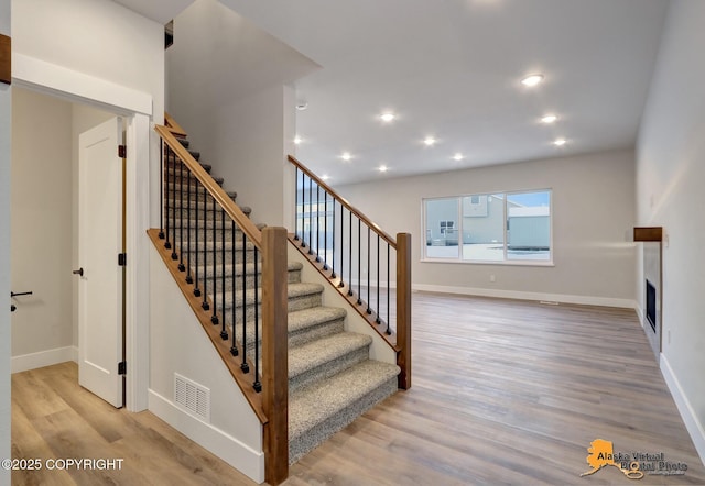 8803 Chalk Hill Loop, Anchorage, AK 99502 - staircase featuring wood finished floors, recessed lighting, and a fireplace