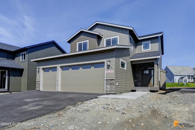 8803 Chalk Hill Loop, Anchorage, AK 99502 - view of front of house with stone siding, board and batten siding, asphalt driveway, and an attached garage