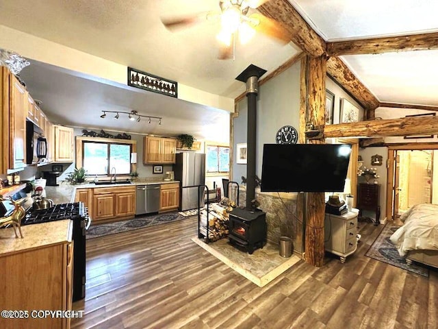 kitchen with black appliances, dark wood-type flooring, a wood stove, sink, and ceiling fan