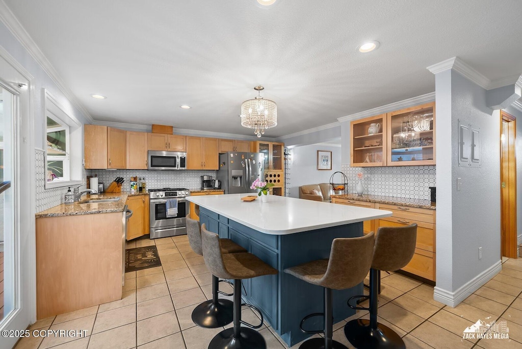 kitchen featuring a kitchen breakfast bar, crown molding, pendant lighting, a kitchen island, and appliances with stainless steel finishes