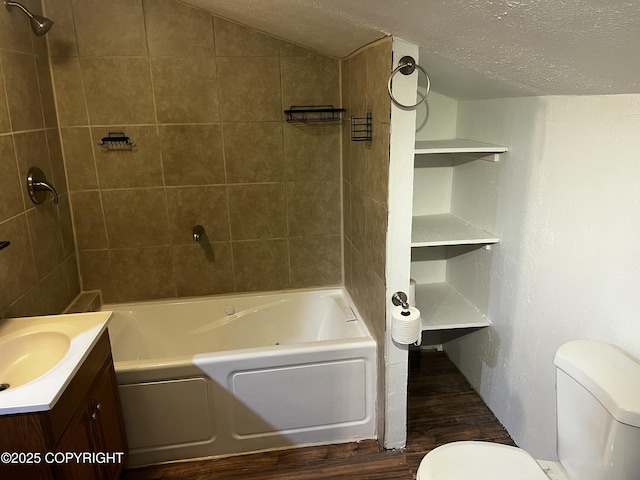 full bathroom with vanity, a textured ceiling, tiled shower / bath combo, hardwood / wood-style floors, and toilet