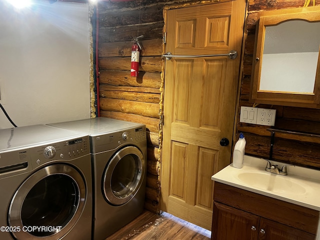 washroom featuring rustic walls, sink, washer and dryer, and wood-type flooring