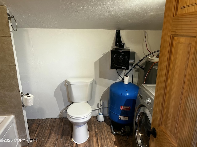 bathroom with hardwood / wood-style floors, toilet, a textured ceiling, and washer / clothes dryer