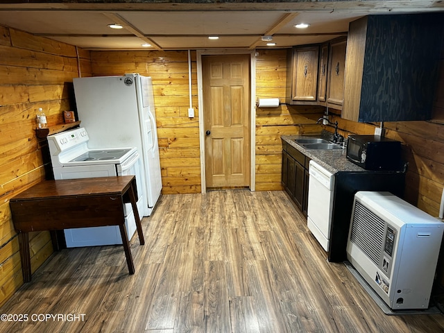 kitchen with dark hardwood / wood-style flooring, white appliances, wood walls, and sink