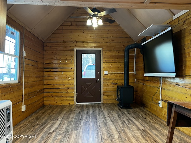 foyer entrance featuring a wood stove, dark wood-type flooring, vaulted ceiling, and wooden walls