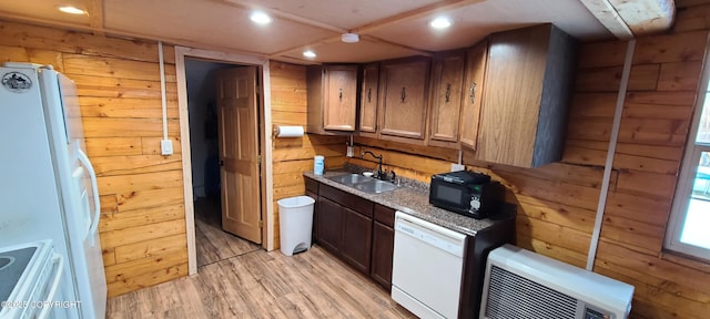 kitchen featuring white appliances, sink, wooden walls, and light hardwood / wood-style flooring