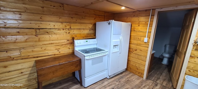 kitchen featuring wooden walls, white appliances, and hardwood / wood-style flooring