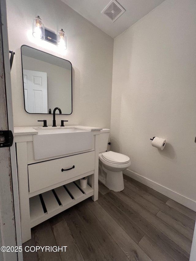 bathroom with toilet, vanity, and hardwood / wood-style floors