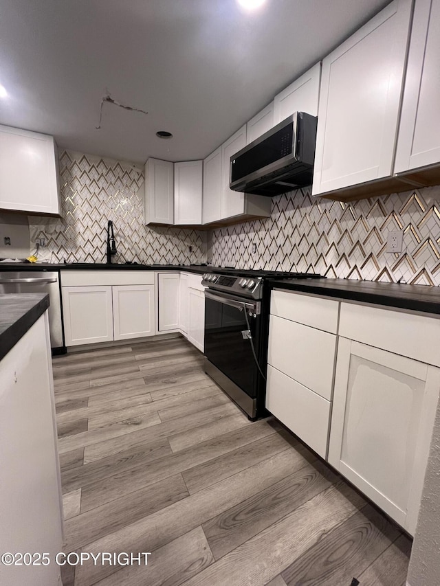 kitchen with sink, extractor fan, white cabinetry, and appliances with stainless steel finishes