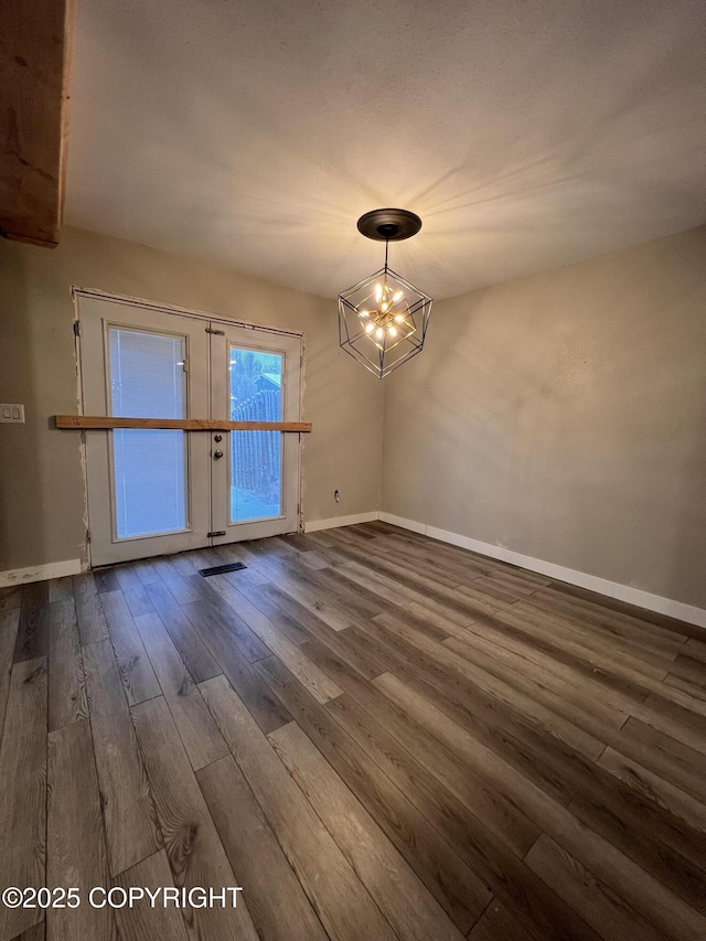 empty room with dark hardwood / wood-style flooring and an inviting chandelier