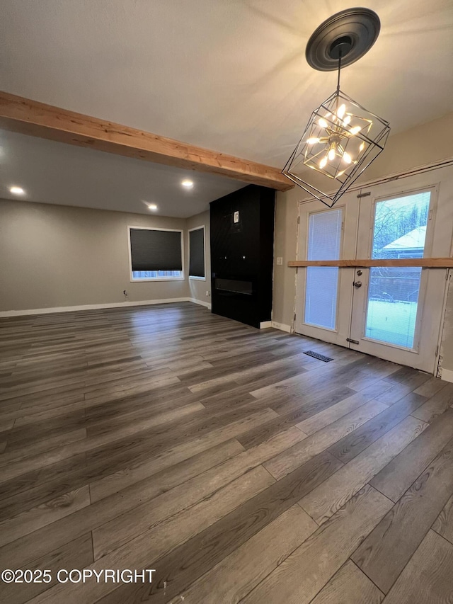 unfurnished living room featuring beam ceiling, dark hardwood / wood-style flooring, and a chandelier