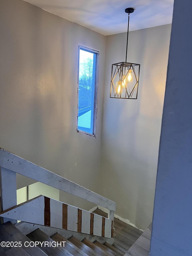 stairs with hardwood / wood-style floors and a notable chandelier