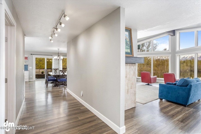 hall featuring a textured ceiling, dark hardwood / wood-style flooring, an inviting chandelier, and lofted ceiling