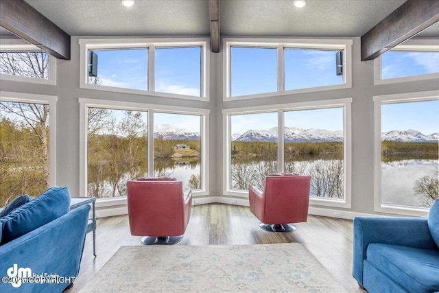 sunroom featuring beamed ceiling and a water and mountain view