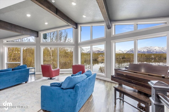 living room with vaulted ceiling with beams, a water and mountain view, a textured ceiling, and light wood-type flooring