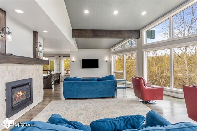 living room with lofted ceiling with beams, wood-type flooring, and a tile fireplace