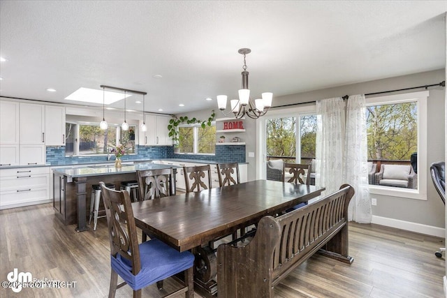 dining area with a chandelier, hardwood / wood-style floors, and a skylight