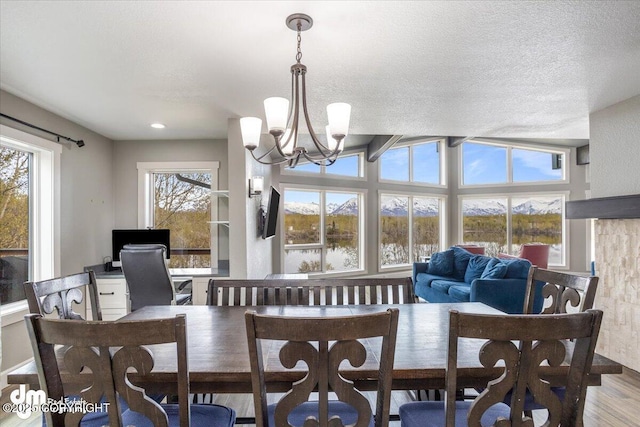 dining area with wood-type flooring, a textured ceiling, and a notable chandelier