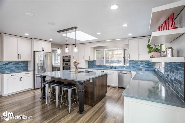 kitchen with a center island, backsplash, sink, appliances with stainless steel finishes, and white cabinetry