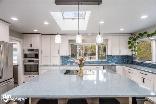 kitchen with a large island, a breakfast bar, appliances with stainless steel finishes, and a skylight