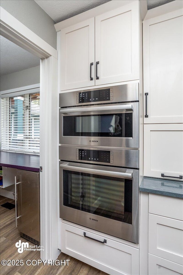 kitchen featuring white cabinetry, stainless steel double oven, and dark hardwood / wood-style floors