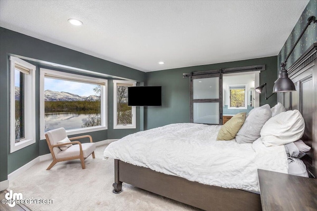 bedroom featuring a barn door, light colored carpet, a textured ceiling, and multiple windows