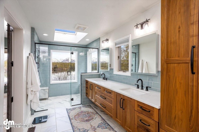 bathroom featuring a skylight, a shower with door, vanity, and tile patterned flooring