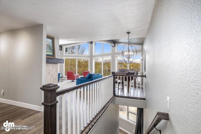 stairs with a healthy amount of sunlight, hardwood / wood-style flooring, vaulted ceiling, and a notable chandelier