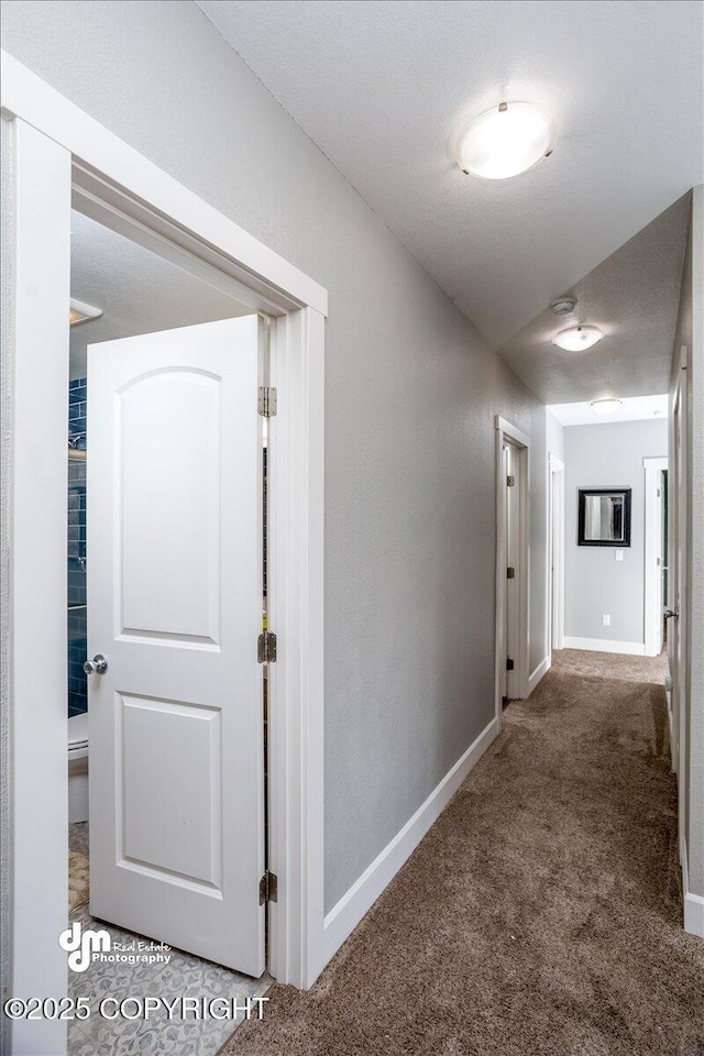 hall with dark carpet and a textured ceiling