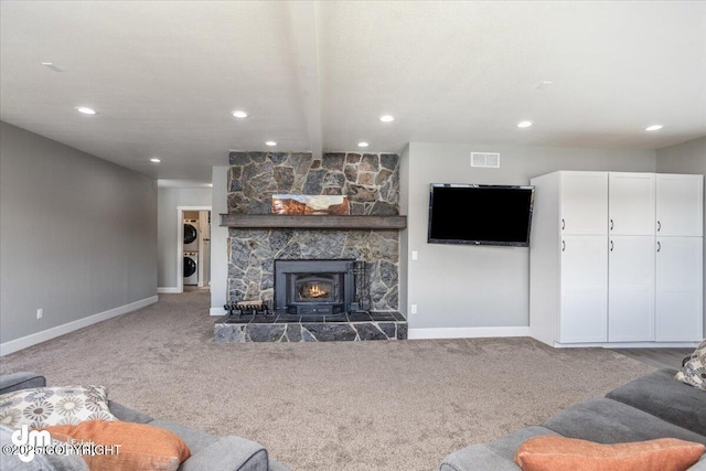 living room featuring carpet flooring, beam ceiling, stacked washing maching and dryer, and a wood stove