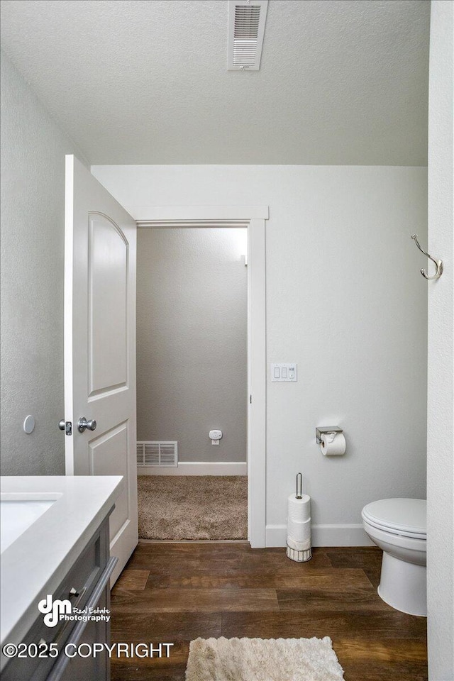 bathroom with vanity, toilet, and wood-type flooring