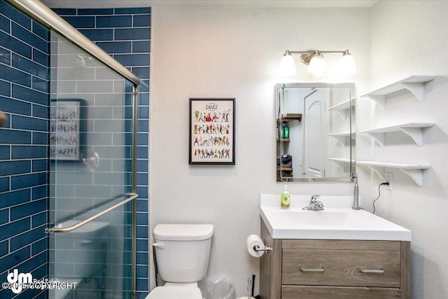 bathroom with vanity, toilet, and a shower with door