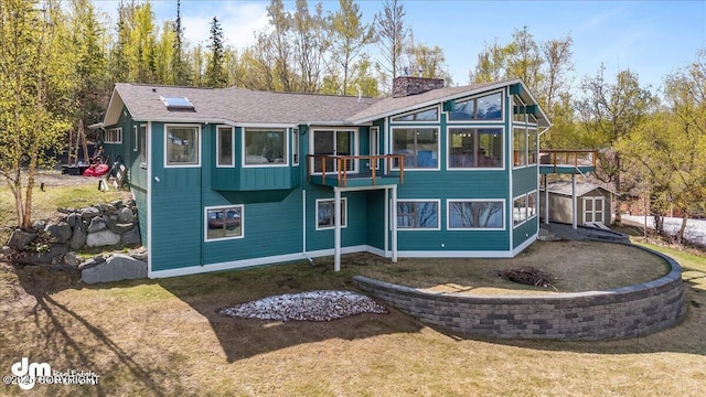 rear view of property with a lawn, a sunroom, and a storage shed