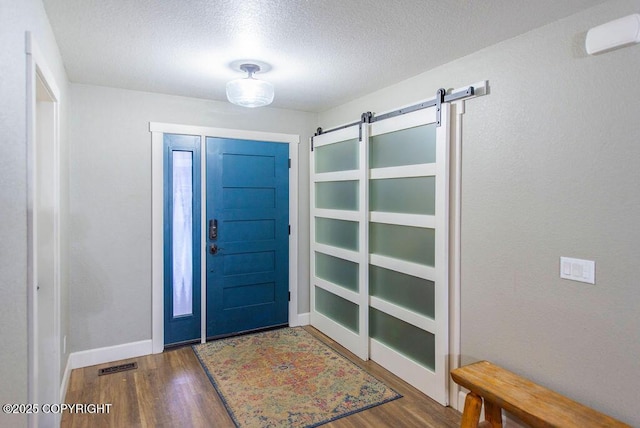 foyer entrance featuring a barn door, dark hardwood / wood-style flooring, and a textured ceiling