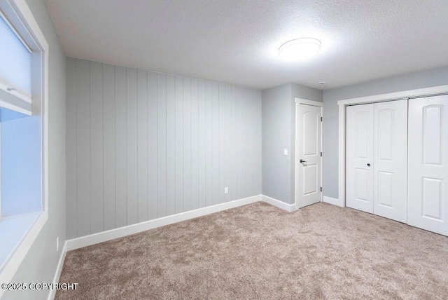 unfurnished bedroom with light carpet, a textured ceiling, and a closet