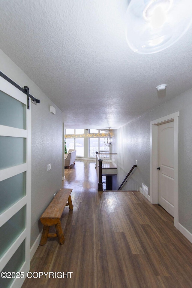 interior space featuring built in shelves, a barn door, dark hardwood / wood-style floors, a textured ceiling, and a notable chandelier