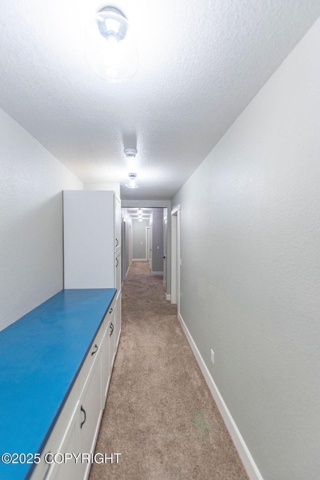 corridor featuring light carpet and a textured ceiling