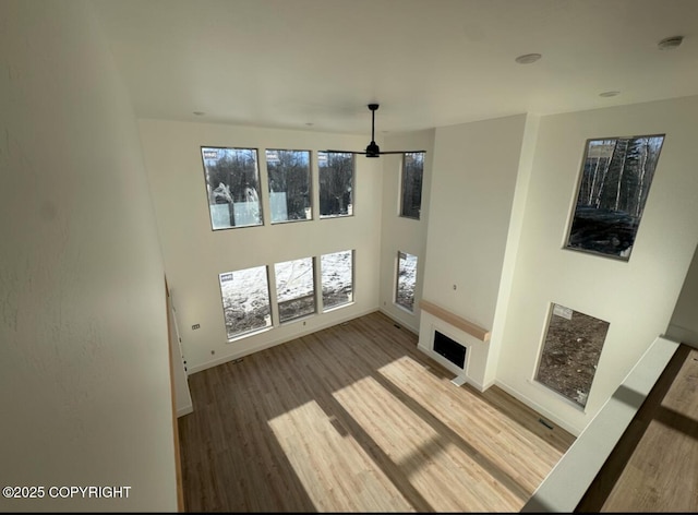 unfurnished living room featuring a fireplace, wood finished floors, a towering ceiling, and baseboards