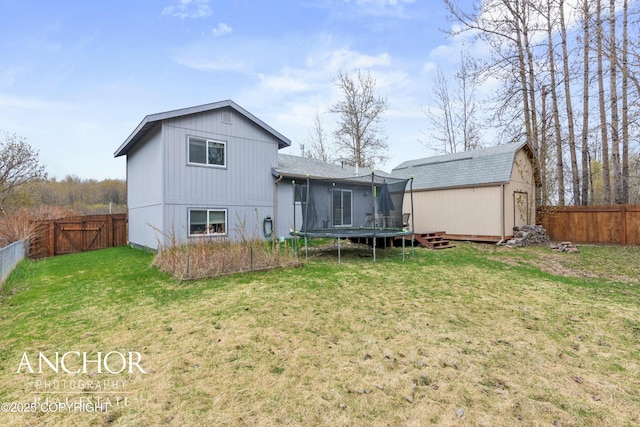 rear view of house featuring a storage shed, a trampoline, and a yard