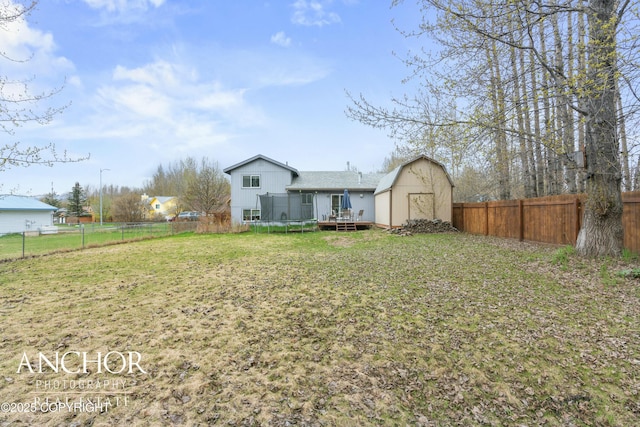 view of yard with a wooden deck, an outbuilding, and a trampoline