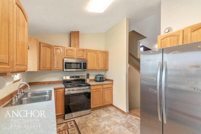 kitchen with light brown cabinets, sink, vaulted ceiling, and appliances with stainless steel finishes