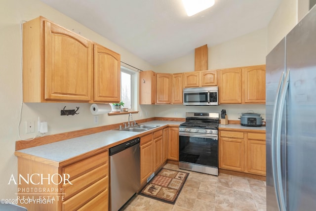 kitchen with light brown cabinetry, sink, lofted ceiling, and appliances with stainless steel finishes