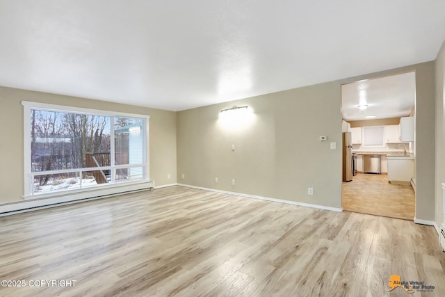 interior space featuring baseboard heating, light hardwood / wood-style flooring, and sink