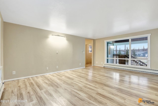 unfurnished room with baseboard heating and light hardwood / wood-style floors