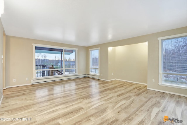 spare room featuring a baseboard radiator, light hardwood / wood-style flooring, and plenty of natural light