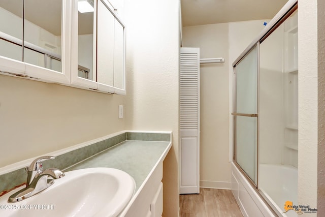 bathroom with hardwood / wood-style flooring, vanity, and combined bath / shower with glass door