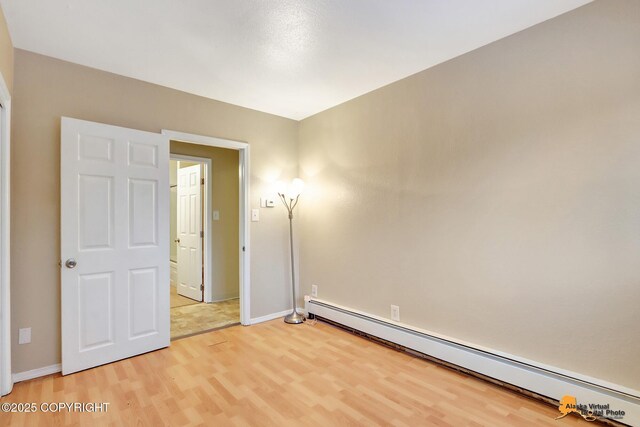 unfurnished room with hardwood / wood-style flooring and a baseboard radiator