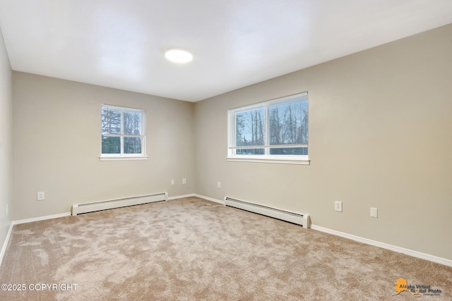 spare room featuring baseboard heating, a wealth of natural light, and light carpet